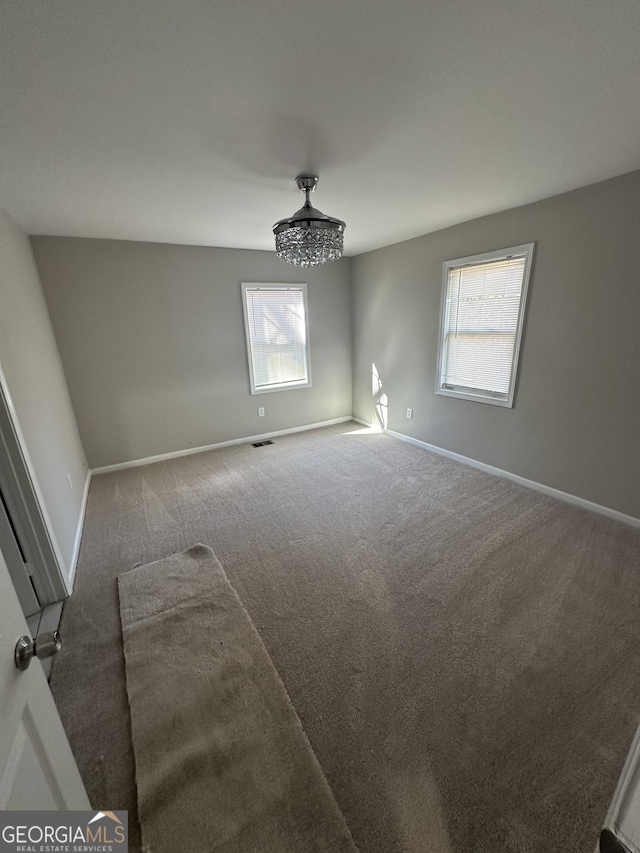 carpeted empty room with visible vents and baseboards