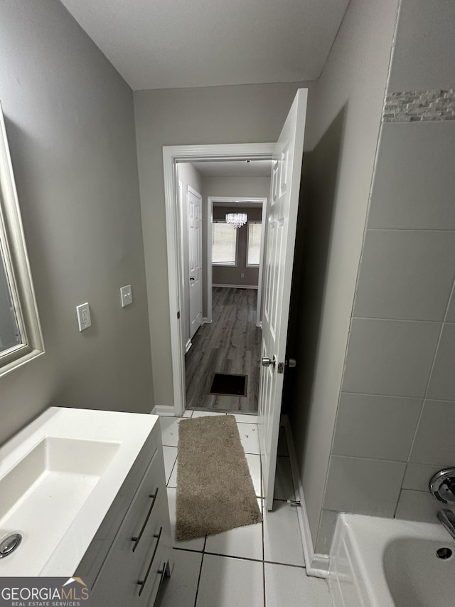 full bath featuring an inviting chandelier, tile patterned flooring, vanity, and baseboards