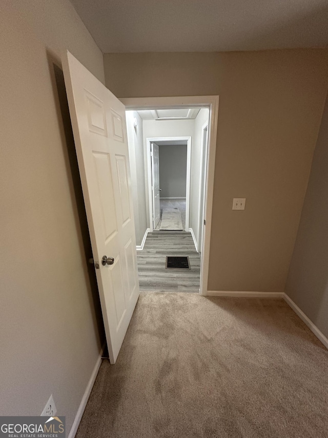 corridor featuring carpet floors, visible vents, and baseboards