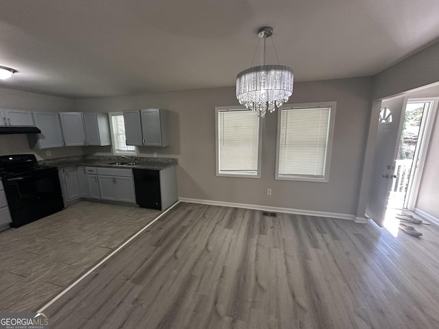 kitchen with black appliances, light wood-type flooring, and a sink