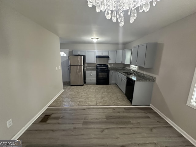 kitchen with baseboards, visible vents, a sink, and black appliances