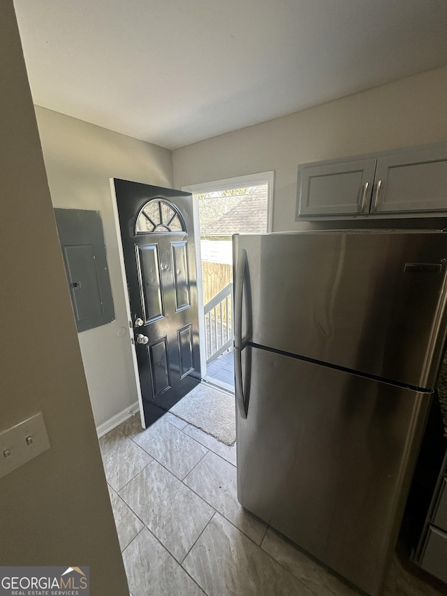 kitchen featuring freestanding refrigerator, gray cabinets, electric panel, and baseboards