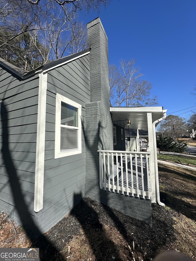 view of side of property featuring crawl space, a porch, and a chimney