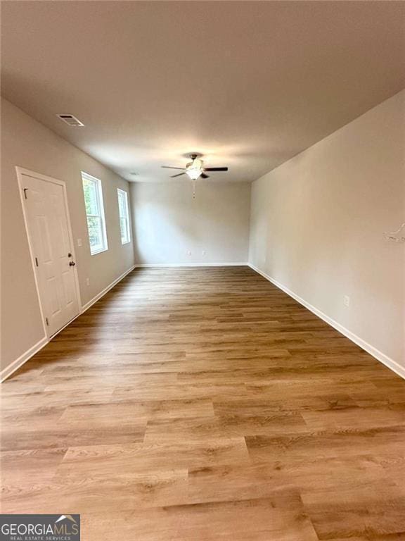 interior space featuring a ceiling fan, baseboards, visible vents, and wood finished floors