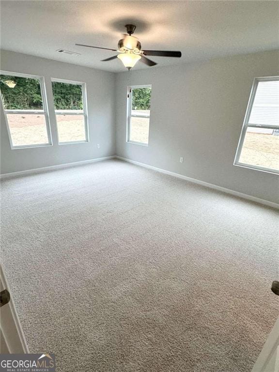 empty room featuring a textured ceiling, carpet floors, a ceiling fan, and baseboards