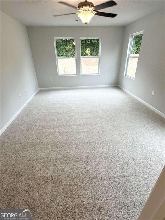 empty room featuring carpet floors, baseboards, and a ceiling fan