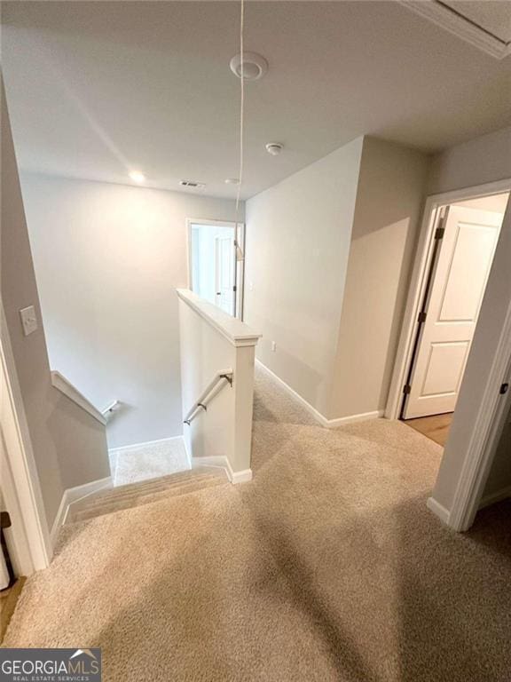 staircase with carpet flooring, attic access, and baseboards