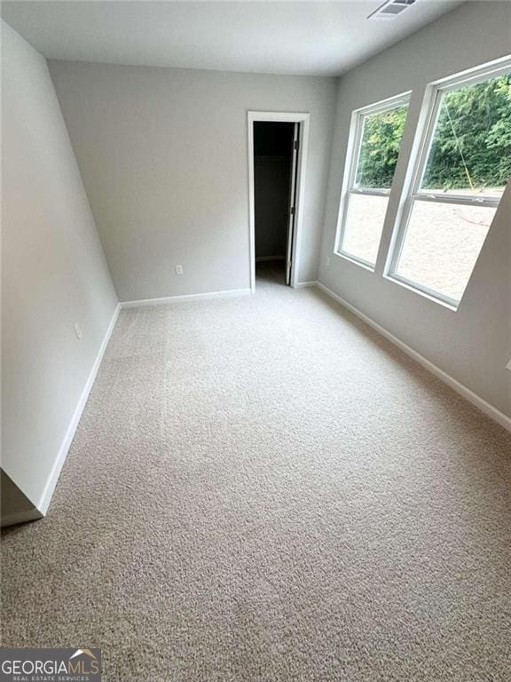 spare room featuring light carpet and baseboards