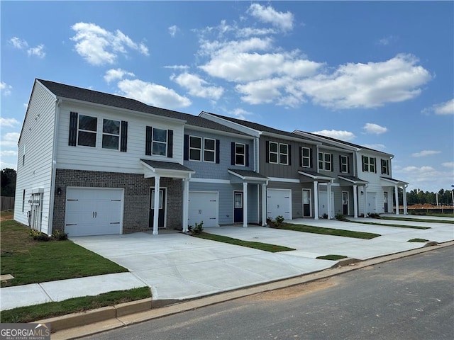 multi unit property with brick siding, driveway, and an attached garage