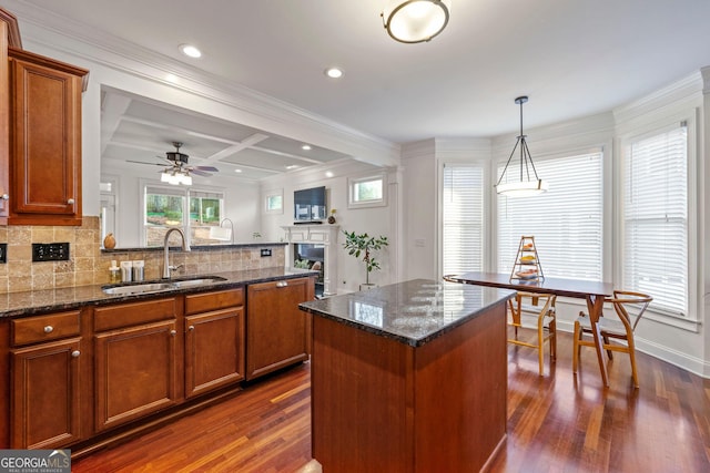 kitchen featuring a peninsula, tasteful backsplash, brown cabinetry, and a sink