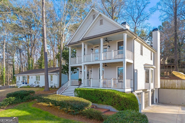 view of front of house with a chimney, covered porch, a ceiling fan, a balcony, and driveway