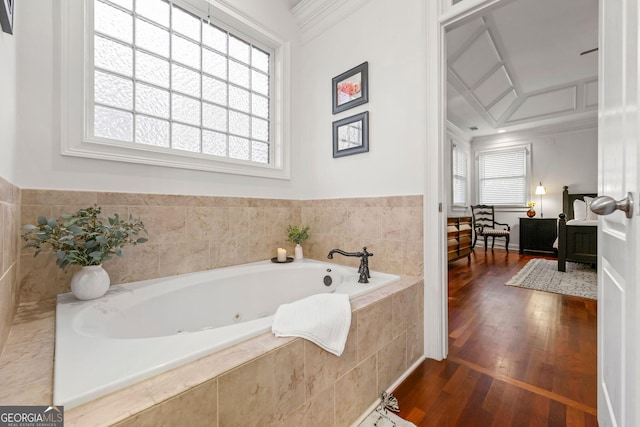 full bathroom with a jetted tub, wood finished floors, a wealth of natural light, and crown molding