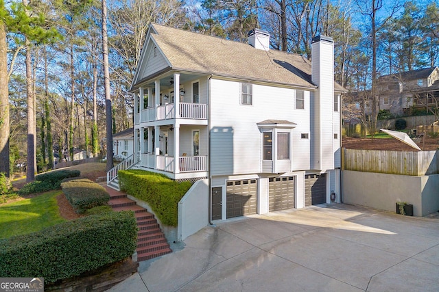 view of home's exterior with an attached garage, a balcony, stairs, concrete driveway, and a chimney