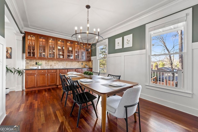 dining room with a chandelier, a decorative wall, a wainscoted wall, dark wood-style flooring, and crown molding