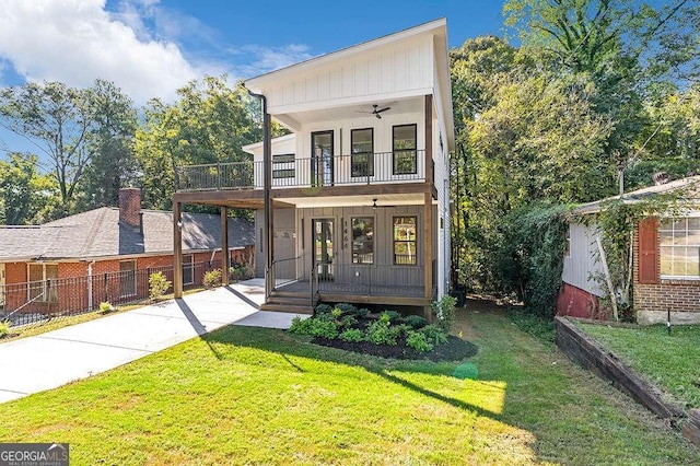 view of front of property with a balcony, ceiling fan, a porch, a front lawn, and board and batten siding