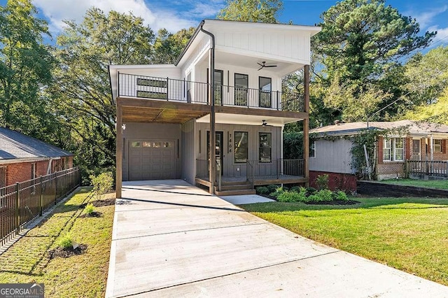 view of front facade featuring driveway, a balcony, covered porch, fence, and a front yard