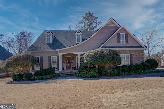 view of front of house with stone siding, a porch, and a front yard