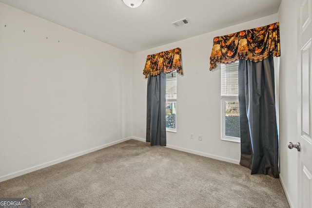 carpeted empty room featuring visible vents and baseboards