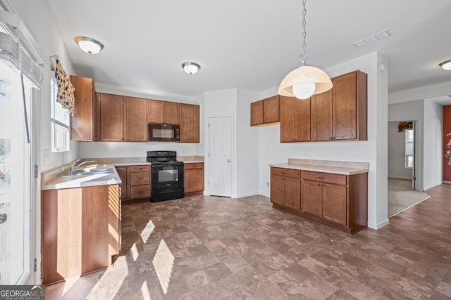 kitchen with brown cabinets, light countertops, visible vents, a sink, and black appliances