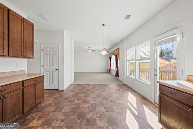 kitchen with a ceiling fan, light countertops, pendant lighting, and visible vents