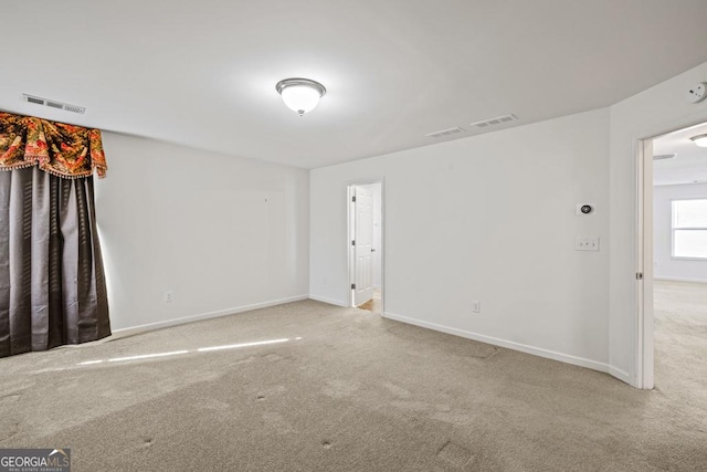 empty room featuring carpet, visible vents, and baseboards