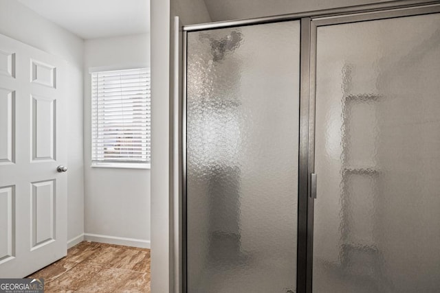 bathroom with a shower stall and baseboards