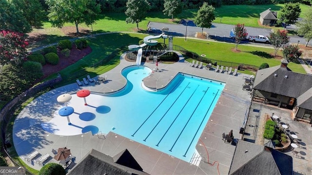 community pool with a water slide, a patio area, and a lawn