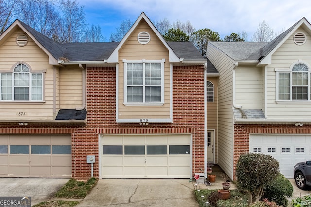 townhome / multi-family property with a garage, concrete driveway, and brick siding