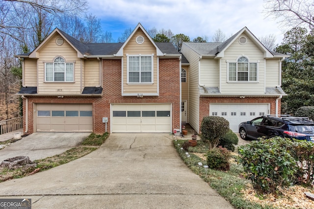 view of property with brick siding, driveway, and an attached garage