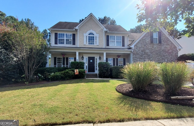 colonial house featuring brick siding, a porch, and a front yard