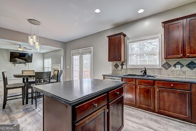 kitchen featuring dark countertops, a healthy amount of sunlight, backsplash, and a sink