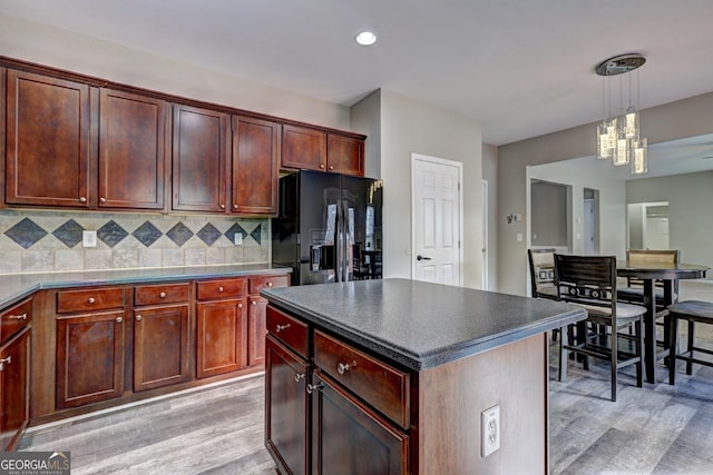 kitchen with light wood-style floors, dark countertops, black fridge with ice dispenser, and backsplash