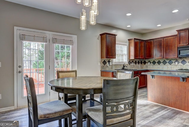 kitchen with black microwave, a sink, light wood-type flooring, and backsplash