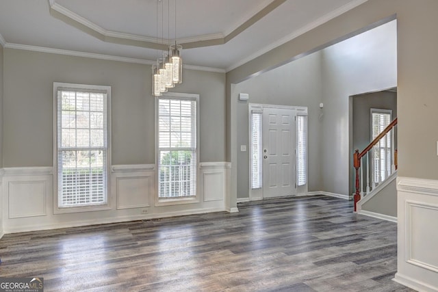 entrance foyer featuring stairs, dark wood-type flooring, wainscoting, and a raised ceiling