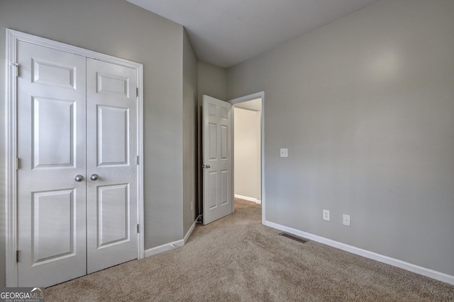 unfurnished bedroom with carpet, a closet, visible vents, and baseboards