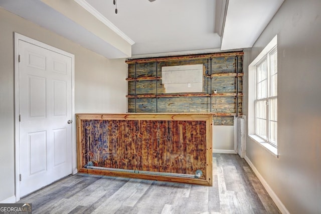 bar featuring baseboards, wood finished floors, and crown molding