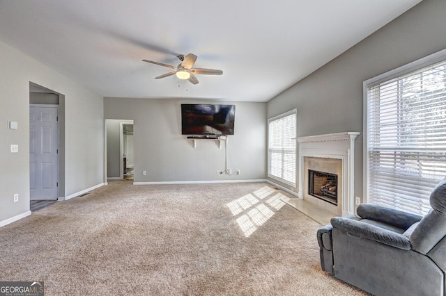 carpeted living area with ceiling fan, a premium fireplace, and baseboards