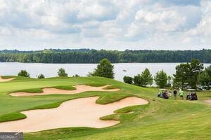 view of home's community featuring a water view, a lawn, and golf course view