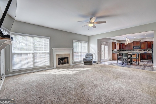 unfurnished living room featuring a high end fireplace, light colored carpet, ceiling fan, and recessed lighting