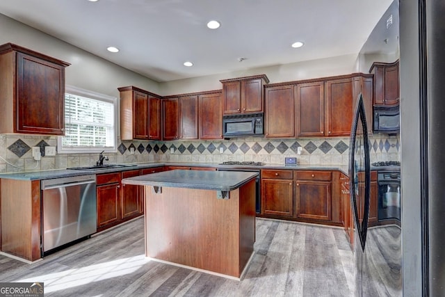 kitchen with light wood-style floors, a sink, black microwave, dishwasher, and fridge