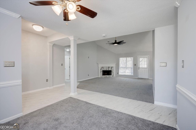 unfurnished living room with vaulted ceiling, carpet floors, a fireplace, and ornate columns