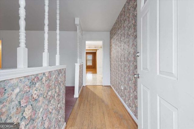 hallway with wallpapered walls, baseboards, and wood finished floors