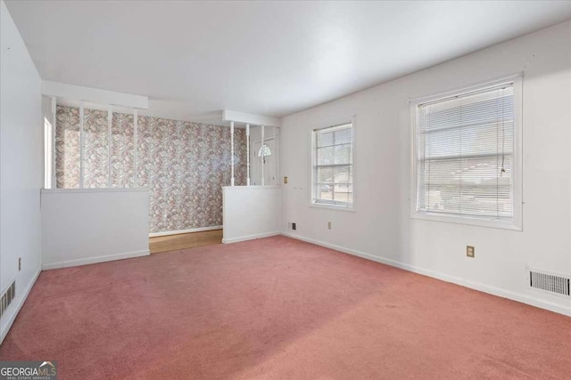 carpeted empty room featuring baseboards and visible vents