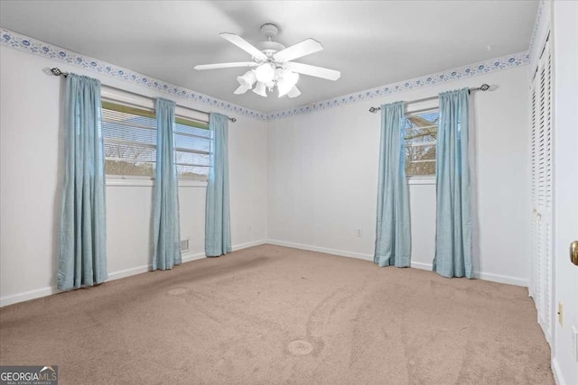 carpeted spare room with ceiling fan and baseboards