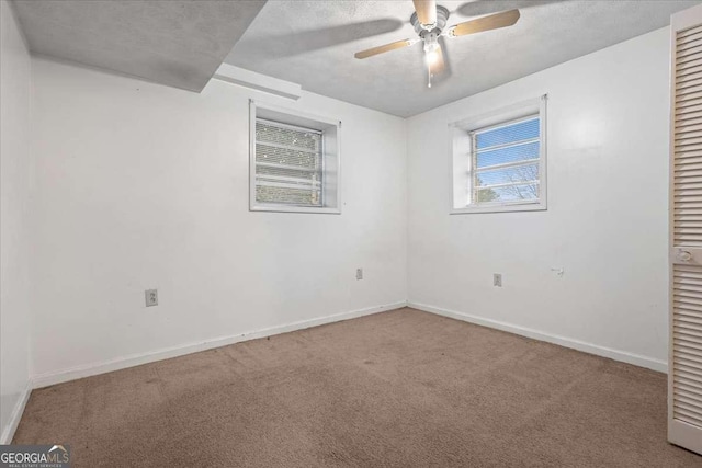 carpeted spare room with ceiling fan, baseboards, and a textured ceiling