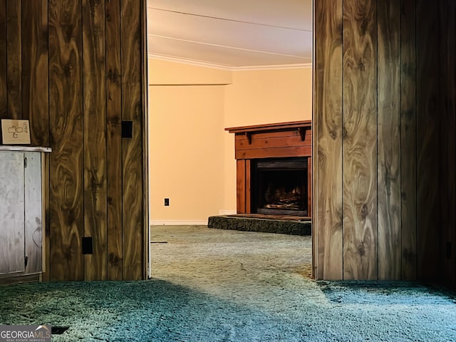 unfurnished living room with carpet floors, a fireplace with raised hearth, and crown molding