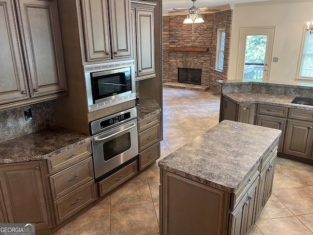 kitchen with tasteful backsplash, ceiling fan, stainless steel appliances, dark brown cabinets, and a fireplace