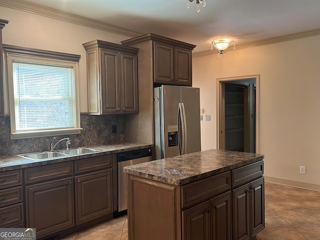 kitchen featuring stainless steel appliances, dark countertops, a sink, and ornamental molding