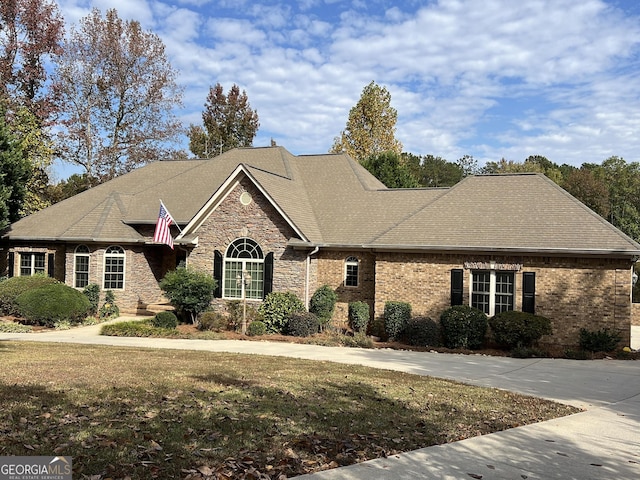 view of front of property featuring stone siding, roof with shingles, and brick siding