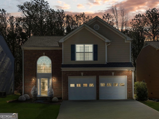 traditional-style house with a garage, brick siding, and driveway